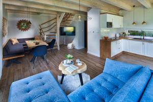 a living room with a blue couch and a table at SosnowoMi - Całoroczne domy na wynajem in Lubiatowo