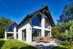 a white house with a black roof at SosnowoMi - Całoroczne domy na wynajem in Lubiatowo