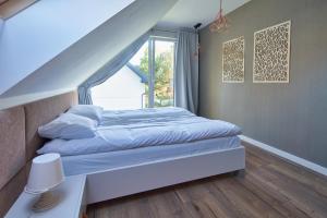 een slaapkamer met een bed met blauwe lakens en een raam bij SosnowoMi - Całoroczne domy na wynajem in Lubiatowo