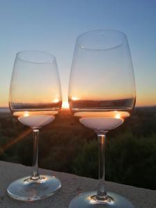 two wine glasses sitting on a ledge with the sunset at La Vecchia Fornace in SantʼAnna Arresi