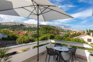 a patio with a table and chairs and an umbrella at Happy Apartments Baška in Baška