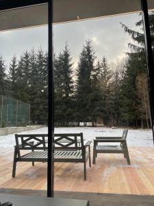 dos bancos sentados en una terraza de madera con nieve en Vila M15, en Topliţa