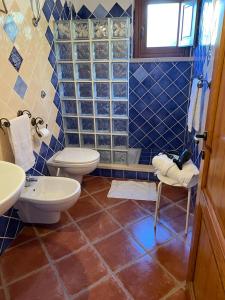 baño de azulejos azules con 2 aseos y ducha en La Vecchia Fornace, en SantʼAnna Arresi