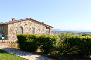 una casa de piedra con arbustos delante de ella en Agriturismo Suite del Conte en San Vincenzo