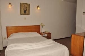- une chambre avec un lit blanc et une tête de lit en bois dans l'établissement Residencial D. João III, à Ponta Delgada