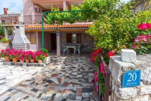 a house with a patio with flowers and plants at Apartman Budimir in Cres