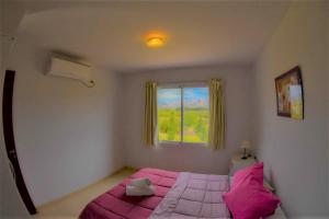 1 dormitorio con cama rosa y ventana en Cabañas La Emilia Apart, en Valle Grande 47 fotos más