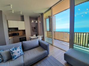 a living room with a couch and a balcony at Blue Bay apartment Green Coast in Palasë