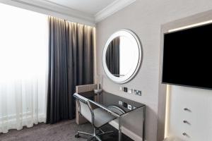 uma casa de banho com um espelho, uma cadeira e uma secretária. em Radisson Blu Hotel, Leeds City Centre em Leeds