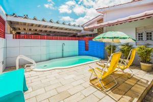 a swimming pool with two chairs and an umbrella at Pousada Ciranda in Itamaracá
