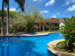 a swimming pool in front of a house with palm trees at Soleil Studio Ocotal in Sardinal