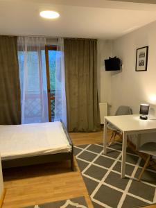a bedroom with a bed and a desk and a table at Przystanek Gubałówka -Guest House Zakopane in Zakopane