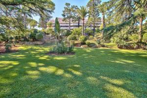 a green yard with trees and a building in the background at LE MIRAMAR Nice - Clim, Parking, Wifi et piscine in Nice