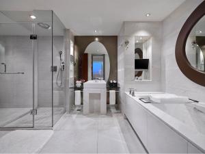 a white bathroom with a shower and a sink at Gehua New Century Hotel Beijing in Beijing