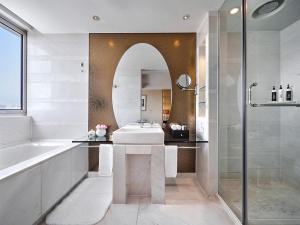Un baño con bañera, lavabo y espejo. en Gehua New Century Hotel Beijing, en Beijing