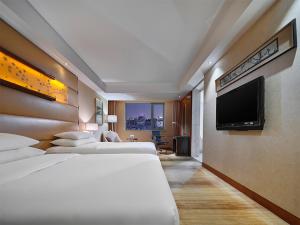 a hotel room with three beds and a flat screen tv at Gehua New Century Hotel Beijing in Beijing