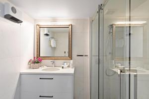 a white bathroom with a sink and a shower at Queenstown House Lakeside in Queenstown