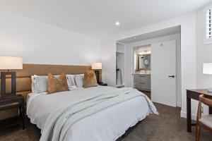 a bedroom with a large white bed and a desk at Queenstown House Lakeside in Queenstown