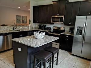 a kitchen with a counter with a refrigerator and stools at Luxurious Modern Villa near Disney with Theater, Pool and Spa in Encore Resort at Reunion in Orlando