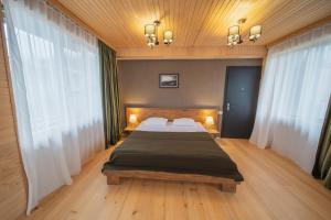 a bedroom with a large bed and two windows at Hotel Old House Mestia in Mestia