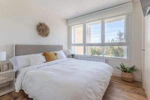 a white bedroom with a large bed and a window at FIRST LINE SEA VIEWS - Club & Pool & Parking by ALOHA Bilbao in Sopelana