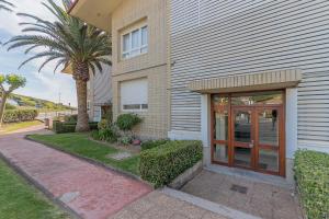 a house with a glass door and a palm tree at FIRST LINE SEA VIEWS - Club & Pool & Parking by ALOHA Bilbao in Sopelana