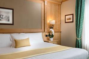 a bedroom with a white bed with a green curtain at Hotel Cristallo in Bormio