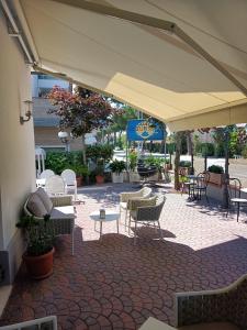 um pátio com cadeiras e mesas e um grande guarda-sol em Hotel Belturismo em Bellaria-Igea Marina
