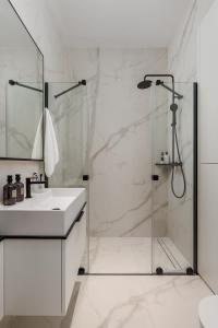 a white bathroom with a shower and a sink at Plaza Apartments in Opatija
