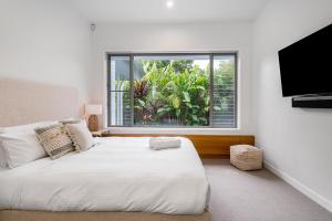 バイロンベイにあるKaylani Beach House 1の大きな白いベッドと窓のある寝室