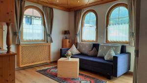 Appartements Haus Olympia في إنسبروك: غرفة معيشة مع أريكة زرقاء ونوافذ