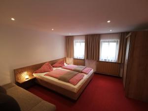 a bedroom with a bed and a couch and two windows at Vorderhof in Sankt Martin am Tennengebirge