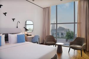 ドバイにあるLemon Tree Hotel, Jumeirah Dubaiのベッドと大きな窓が備わるホテルルームです。