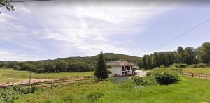 uma pequena casa branca num campo com uma cerca em Favetto Family Ranch em Rueglio