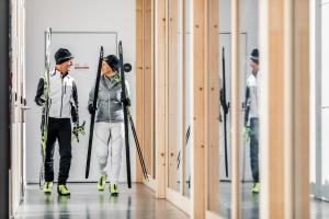a man and a woman walking down a hallway with skis at Nordic Hostel in Lenzerheide