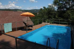 una piscina con una sombrilla en una terraza en Het gevoel van vrijheid tussen bos en dorp, en Beaulieu-sur-Dordogne