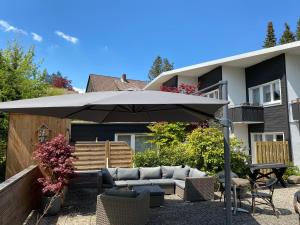 a patio with an umbrella in front of a house at Hotel Haus am Hochwald in Hahnenklee-Bockswiese