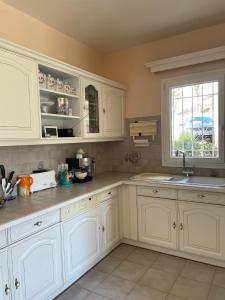 eine Küche mit weißen Schränken, einem Waschbecken und einem Fenster in der Unterkunft Villa 180 m2 piscine in Draguignan