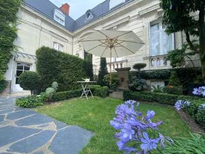 a garden with a table and an umbrella and purple flowers at BULLES DE LOIRE in Saumur