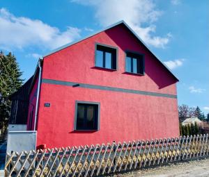 une maison rouge avec une clôture devant elle dans l'établissement Ferienhaus Papstdorf, à Gohrisch