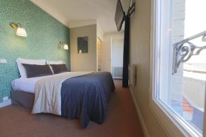 a bedroom with a bed and a large window at Hôtel Azur in Reims