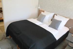 uma cama grande com lençóis e almofadas preto e branco em Hotel Petite B&B em Haderslev