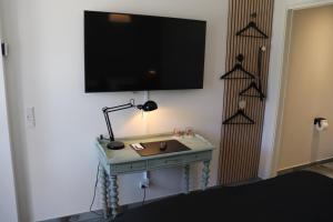 Habitación con mesa y TV en la pared. en Hotel Petite B&B en Haderslev