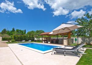 a swimming pool with an umbrella and a table and chairs at House Marino 2069 in Pula
