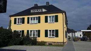 a yellow house with green shutters on a street at Genesungsort Landhaus Dammert in Oppach