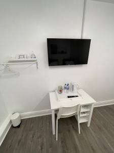 a white table with a tv on a white wall at County road rooms in Liverpool