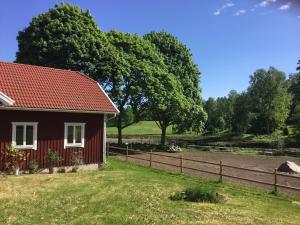 una casa roja con una valla al lado de un campo en Hultets gård, en Lerdala