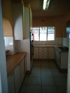 a small kitchen with white cabinets and a window at 4ways Youth Hostel in Johannesburg