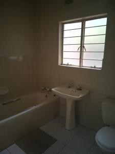 a bathroom with a tub and a sink and a window at 4ways Youth Hostel in Johannesburg