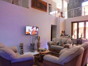 a living room with chairs and a tv on a wall at Royal Castle Guest House in Windhoek